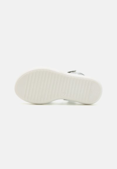 Vit gummiyttersula med texturerade grepplinjer. Slät yta med lätt glans, minimalistisk design. Platt form lämplig för avslappnad användning.