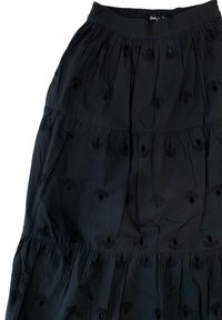 Gonna nera a strati realizzata in tessuto leggero con motivi floreali ricamati e dettagli a intaglio. La vita elastica garantisce comfort.