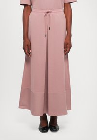 Maxikjole i myk rosa jersey-stoff med avslappet passform, elastisk midjebånd, snøring og sømdetaljer i kanten. Rund silhuett.