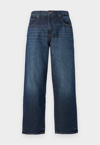 Tumedat sinised denim püksid sirge jala disainiga, nähtava õmblusega, viie taskuga ja nupuga kinnitamine vööl. Sile tekstuur.