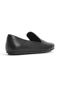 Černá kožená nazouvací bota s elegantním designem, zaoblenou špičkou a texturovanou gumovou podrážkou s malými vyvýšenými tečkami pro lepší přilnavost.