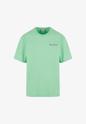 Mintgroene katoenen T-shirt met korte mouwen, ronde hals en een klein zwart "Kani Studios" logo op de linkervoorzijde.