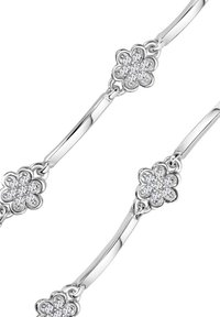 Srebrna bransoletka z ogniwami w kształcie kwiatów, ozdobiona przezroczystymi kamieniami szlachetnymi. Gładkie, błyszczące wykończenie oraz delikatny, zaokrąglony kształt.