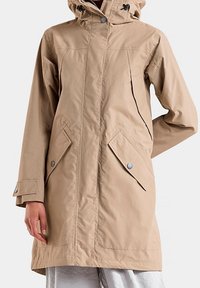 Beige vedenpitävä huppari, jossa on kaksi etutaskua, pikalukot ja suora malli, valmistettu sileästä, kestävästä kankaasta.