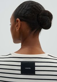 Camicia a righe in tessuto crema e nero; presenta un collo rotondo e un'etichetta quadrata sul retro con il testo "someday."