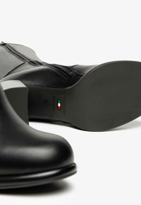 Schwarze Leder-Stiefeletten mit runder Spitze, Reißverschluss und Blockabsatz. Die Sohle hat ein glattes Finish und Markendetails.