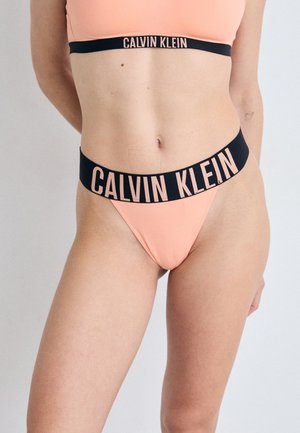Calvin Klein bikini set in perzik met een zwarte tailleband waarop de merknaam in roze letters staat. Glad materiaal met een minimalistisch ontwerp.