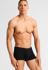 Boxers en coton noir avec une coupe ajustée, dotés d'une ceinture simple et sans motifs ni accents visibles. Le modèle présente une vue de face.