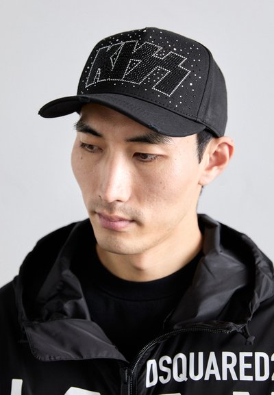 Svart baseballcaps med en teksturert design og rhinestones som stavern "NTS" foran, med en buet skjerm.