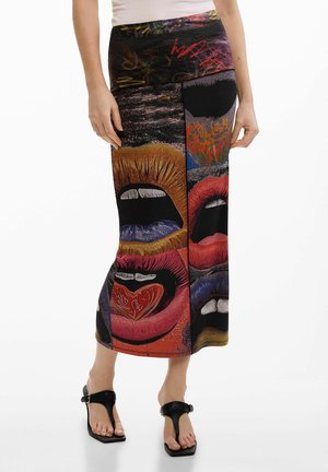 Gonna con grandi stampe grafiche colorate di labbra aperte in rosso, arancione, blu e viola, indossata con sandali neri.