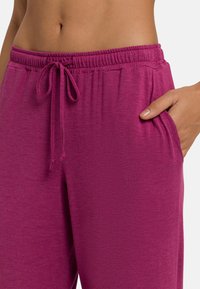 Farkut jogger yang pas di badan berwarna magenta cerah, dilengkapi dengan pinggang elastis dan tali serut serta saku samping. Kain yang lembut dan berpola.