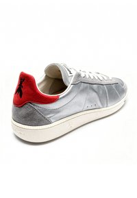Grijze leren sneaker met een rode suède hiel detail, witte veters en een textuur oppervlak. Bevat branding en een rubberen zool.