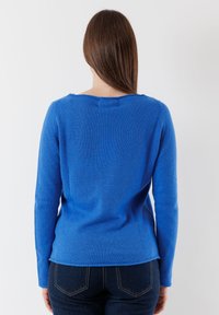 Maglione blu lavorato a maglia con scollatura a coste e maniche lunghe, caratterizzato da una texture liscia e una silhouette leggermente aderente.