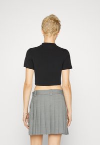 Must have musta lühikeste varrukatega must cropped t-särk. Koos halli volditud seeliku, millel on ruuduline muster, vöökohad ja küljetaskud.