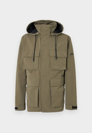 Olivengrønn hettejakke med frontglidelås, fire klafflommer, justerbare håndleddsstropper og svarte snorer på hetten.