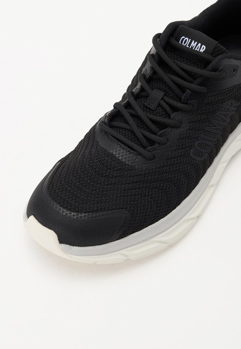 Schwarzer Sportschuh mit einem strukturierten Mesh-Obermaterial, ausgestattet mit schwarzen Schnürsenkeln, einer abgerundeten Spitze und einer weißen Gummisohle. Der Markenname "COLMAR" ist sichtbar.
