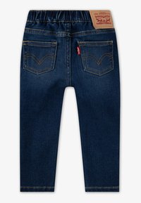 Temno modre hlače iz jeansa z elastičnim pasom, dvema zadnjima žepoma in kontrastnim zlatim šivom. Na pasu označba znamke Levi's.