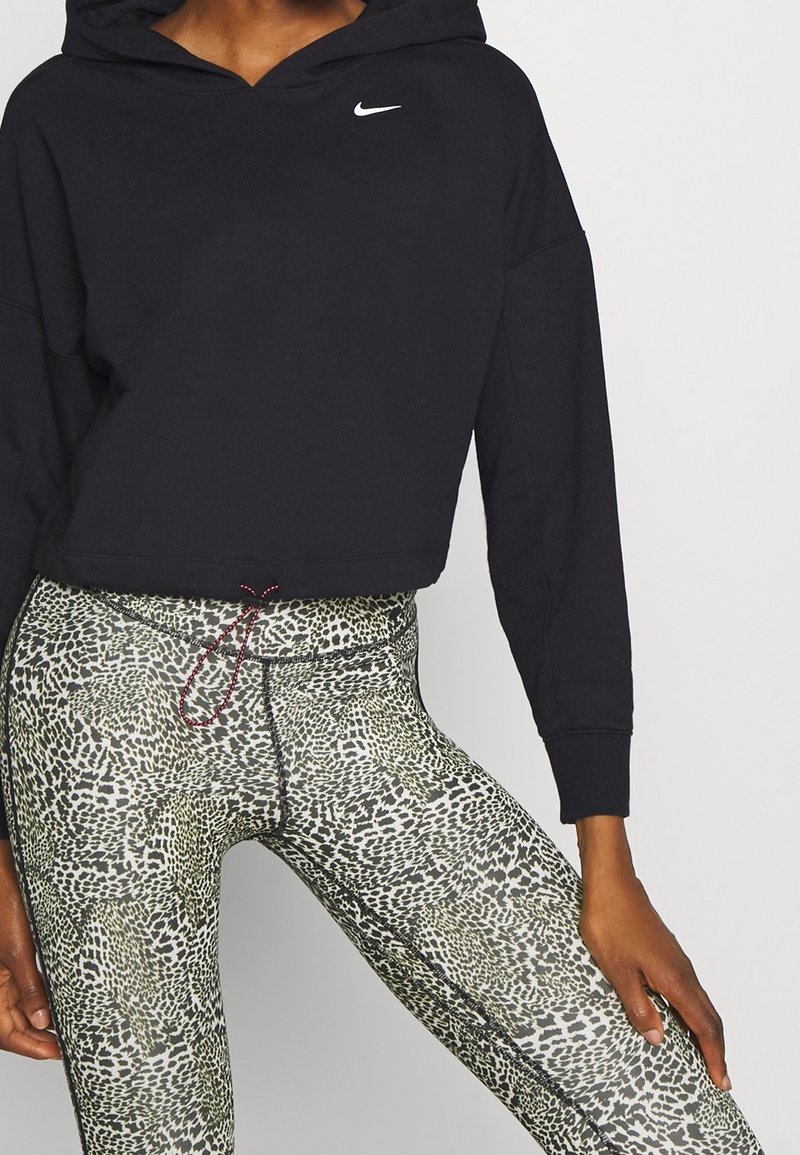 Haut à capuche noir court avec un logo blanc. Leggings en imprimé léopard vert et noir avec une taille à cordon. Texture lisse, design ajusté.