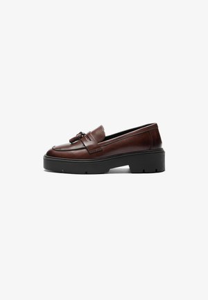 Brown leather loafer with a sleek design, contrasting black platform sole, and decorative tassel accent on the vamp. Smooth texture.