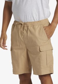 Shorts cargo couleur kaki en tissu léger, dotés d'une taille élastique avec cordon de serrage, de poches latérales et d'une surface texturée.