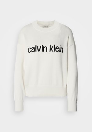 Bjeli pleteni pulover s okruglim izrezom i dugim rukavima, s crnim "calvin klein" logom preko prsa. Mekana tekstura, skraćeni kroj.