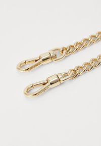 Gold metal chain strap with clip clasps, featuring smooth links and engraved branding. Shiny finish accentuates the polished design.