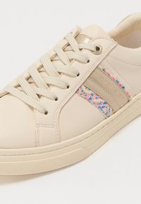 Sneaker in pelle beige con accenti intrecciati multicolore e lacci crema. Presenta una suola in gomma testurizzata e un dettaglio laterale con marchio.