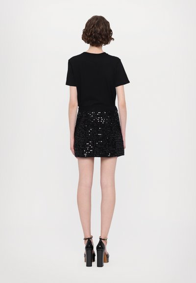 Svart kortärmad t-shirt i kombination med en glittrande svart paljetterad minikjol. Outfiten har en figurnära design och glänsande detaljer.