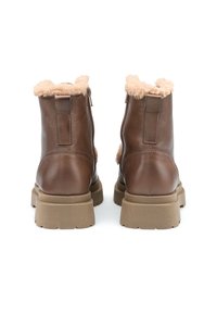 Stivali alla caviglia in pelle marrone con fodera in pelliccia sintetica color beige, suola rigata e cerniera sul retro. Presentano un design robusto e un rinforzo sul tallone.