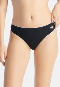 Czarne majtki bikini z białym wykończeniem, o klasycznym kroju i haftowanym logo po prawej stronie. Gładka tekstura.