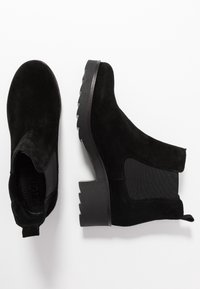 Botas de tobillo de ante negro con paneles elásticos en los laterales y una suela de goma texturizada. Presentan un tacón grueso y un lazo en la parte trasera para facilitar su uso.
