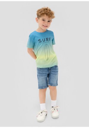 Korte mouwen T-shirt met een verloop van blauw naar groen, voorzien van de tekst "SURF" en een surfplankillustratie. Gecombineerd met denim shorts.
