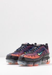 Nike-sneakers med överdel i mesh i en röd till orange gradient, svarta accenter, synlig luftdämpning och slående reflekterande detaljer.