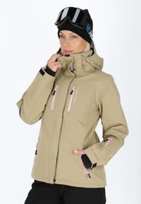 Giacca da sci beige con zip rosa, caratterizzata da un colletto alto, numerose tasche e un design aderente. Tessuto testurizzato con una finitura liscia.