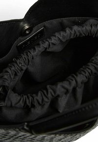 Melnā austā rokassomu ar mīkstu, kroku iekšējo oderi un aizdari ar pogu. Iezīmē gludas tekstūras un neuzkrītošu zīmola etiķeti iekšpusē.