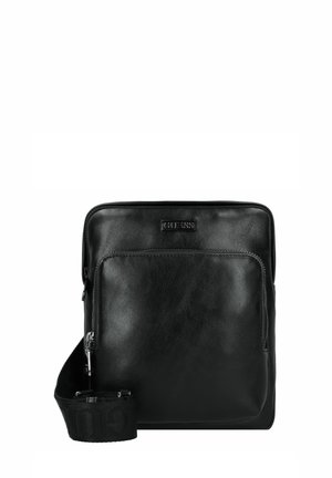 Sac en cuir noir avec une texture lisse, de forme rectangulaire, poche zippée à l'avant et sangle ajustable avec un logo.
