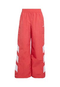 Červené široké športové nohavice vyrobené z ľahkého materiálu, so zvýraznenými bielymi bočnými pruhmi a elastickým pásom.