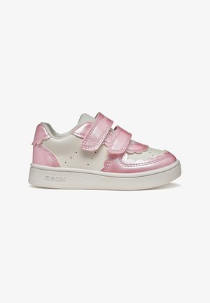 Zapatilla blanca con detalles metálicos en rosa, que cuenta con dos correas ajustables de velcro, diseño decorativo con bordes ondulados y detalles perforados en los lados.