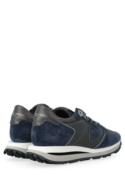 Sneaker in suede e pelle di colore blu navy con un pannello accentato grigio, dettagli riflettenti e suola in gomma texturizzata. Design a profilo basso.