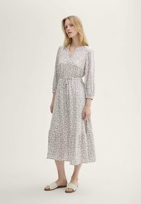 Robe longue et légère avec un motif discret en gris et blanc cassé. Elle présente un décolleté en V, des manches trois-quarts et une taille froncée.