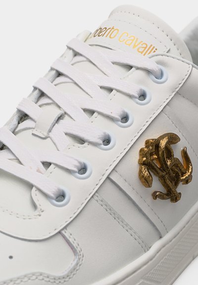 Λευκό δερμάτινο αθλητικό παπούτσι με λευκά κορδόνια, χρυσό λογότυπο "Roberto Cavalli" στη γλώσσα και μεταλλικό χρυσό διαπλεκόμενο εμβληματικό λογότυπο στο πλάι.