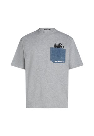 Grå kortærmet t-shirt lavet af bomuld, med en blå denimlomme med et sort grafisk design. Brandnavnet vises på lommen.