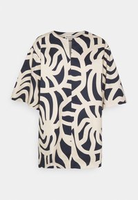 Top a maniche corte realizzato in tessuto leggero, con una base crema e audaci motivi astratti in blu navy, e uno spacco frontale.