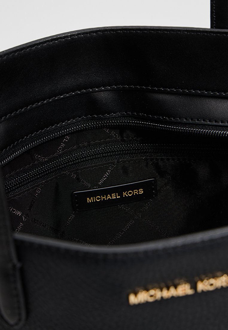 Zwarte leren handtas met een interieur met ritszak en zichtbaar Michael Kors merklabel in goud op de voering en de buitenkant van de tas.
