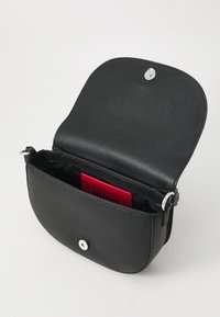 Borsa a spalla in pelle nera con forma arrotondata, chiusura a bottone a pressione e dettagli in hardware argentato lucido. L'interno presenta un porta carte rosso.