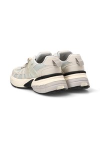 Zapatillas con parte superior de malla en gris claro y crema, que presentan una suela intermedia blanca gruesa, una suela exterior negra y pequeñas lengüetas traseras para ponerlas y quitarlas con facilidad.