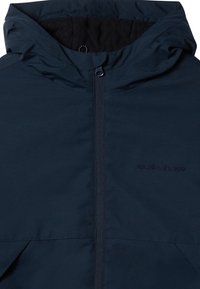 Mörkblå vattentät jacka med framdragkedja, justerbar huva och texturerad innerskikt. Har Quiksilver-logotypen på vänster sida.