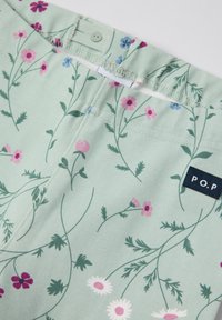 Vihreä kangas, jossa on vaaleanpunaisia, valkoisia ja sinisiä kukkakuoseja. Mukana on etiketti, jossa lukee "P.O.P", ja napitus vyötäröllä.