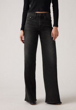Hoge taille zwarte denim jeans met een uitlopende snit, vijf-pocket styling en subtiele vervaging, gecombineerd met een cropped zwart top.