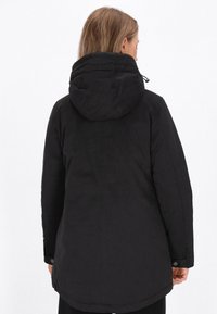 Černý dlouhý kabát s kapucí, s hladkým povrchem a bočními kapsami. Design zahrnuje zakřivený lem a knoflíkové manžety.